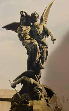Angel statue with wings and figures below.