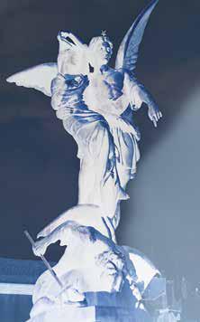 Angel statue illuminated against dark background.